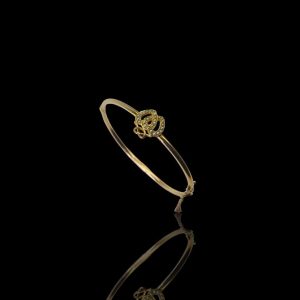 14 krt. Gouden stijve armband gedecoreerd met een dubbel hart, bezet met zaadpareltjes waarboven een strik