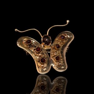 Klederdracht broche in de vorm van een vlinder, met granaten