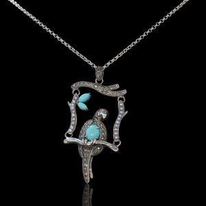 Zilveren papegaai op een schommel met parels, turkoois en een robijn als oog, aan een zilveren collier